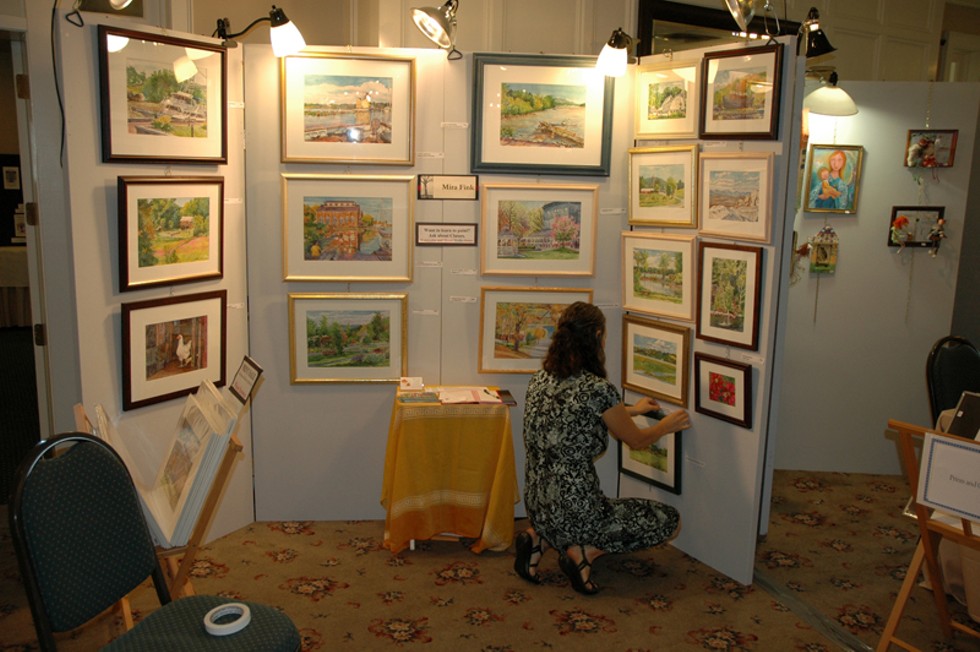 Featured artist hangs paintings at 2012 Fall for Art event.
