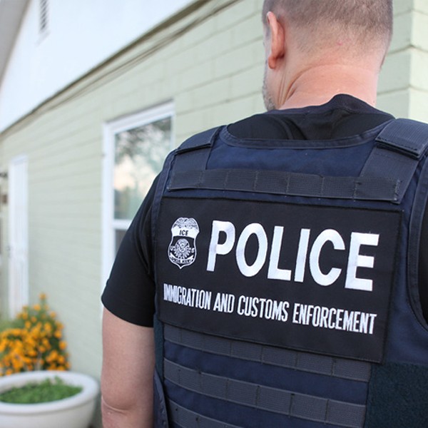 An ICE officer outside a house