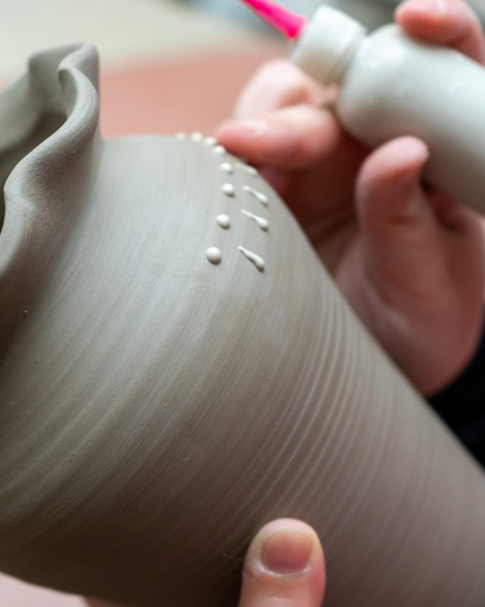 Faith Delgado Demonstrating Slip Trailing or drawing on a clay piece with slip.
