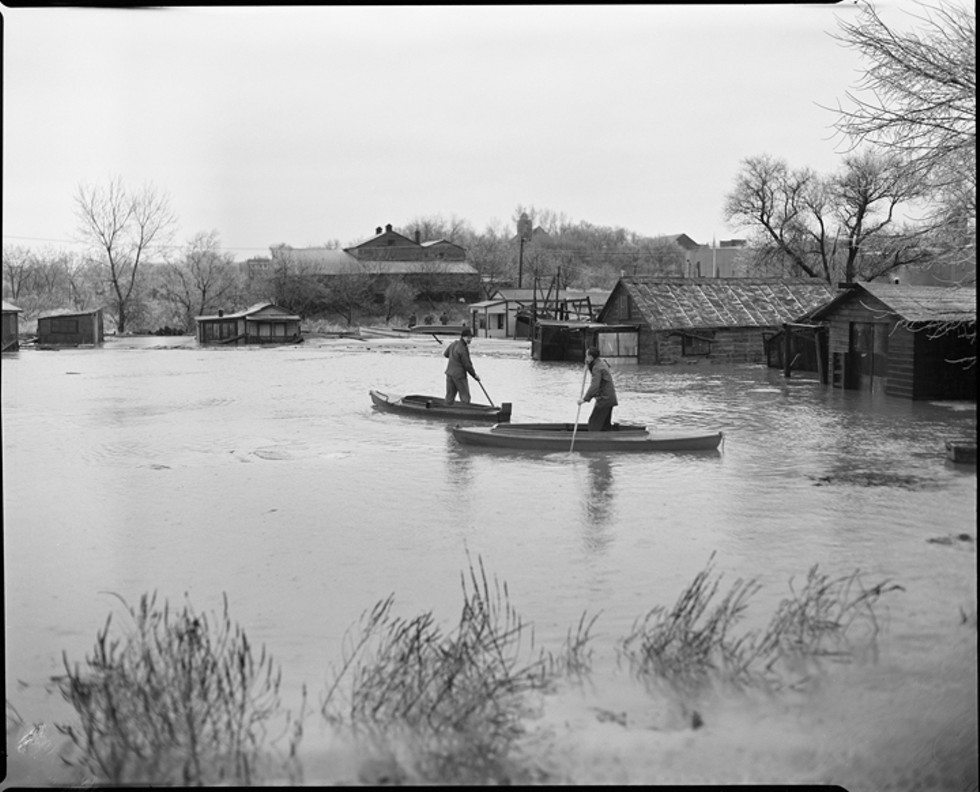 Two men on boats in the Hudson River by Shantytown during a 1948 flood.